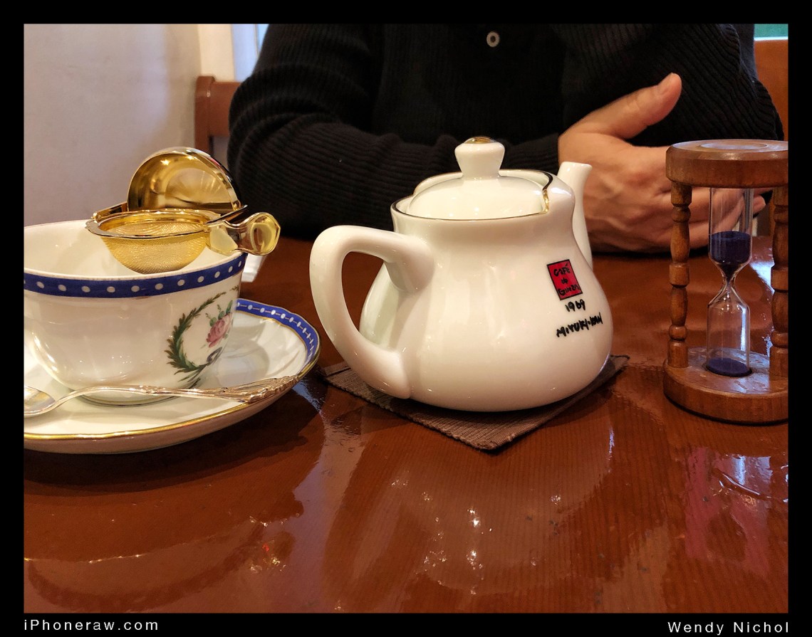 Tea on table in high end tea cafe, Ginza, includes timer, cup, pot and gold strainer.
