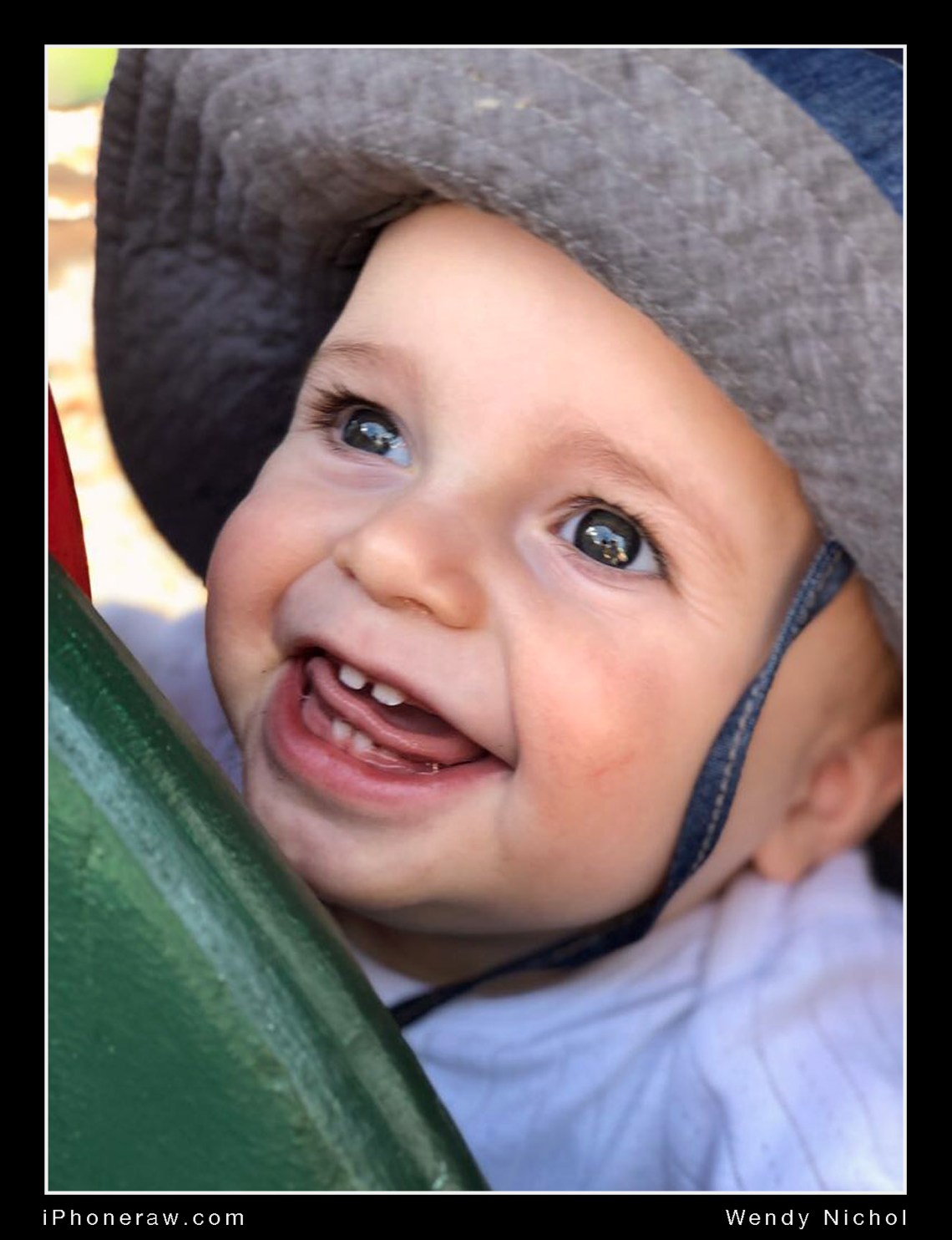 10 month old boy on play gym, smiling broadly, teeth and tongue showing, iphone 8 portrait mode.
