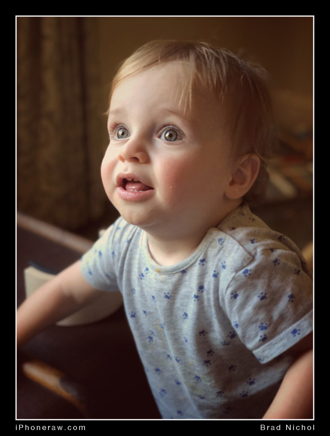 10 month old boy, colour, iPhone X portrait mode, looking left of frame and up, grey shirt.
